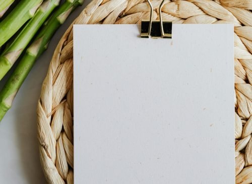Top view of fresh asparagus next to a blank note on a woven mat. Perfect for culinary themes.
